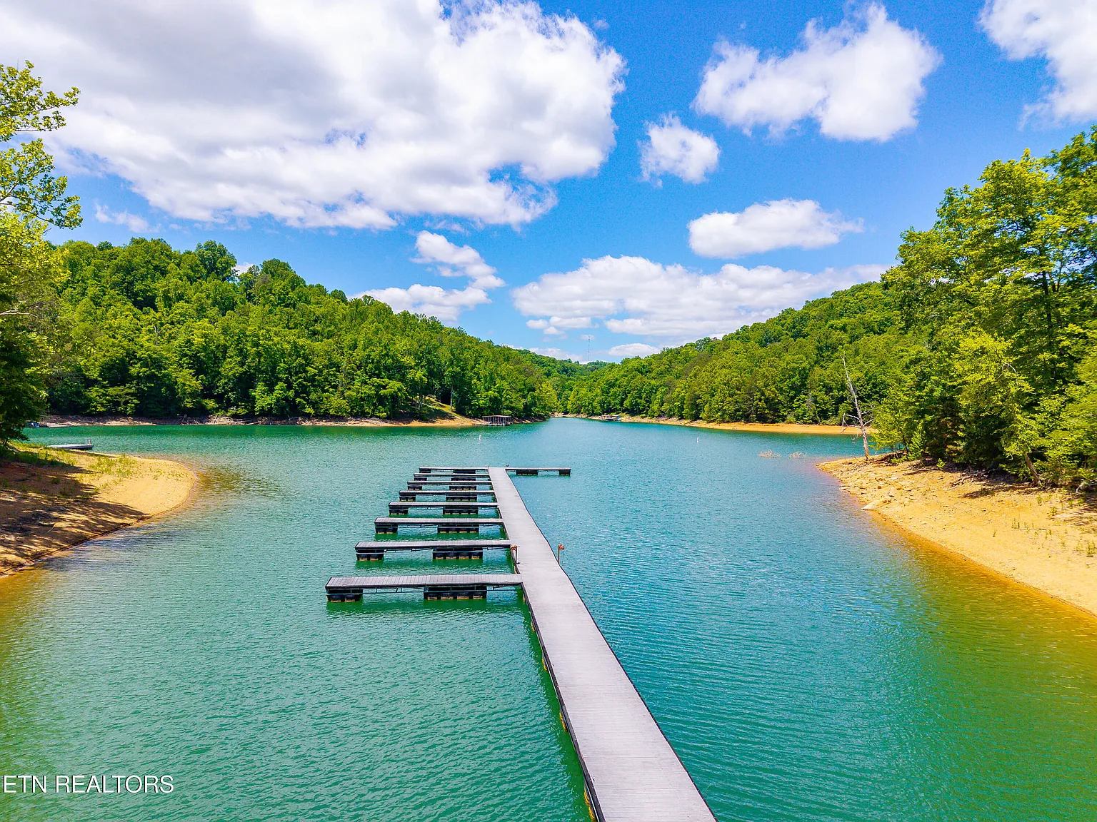 Floating dock with boat slips on a calm turquoise cove surrounded by forested hills
